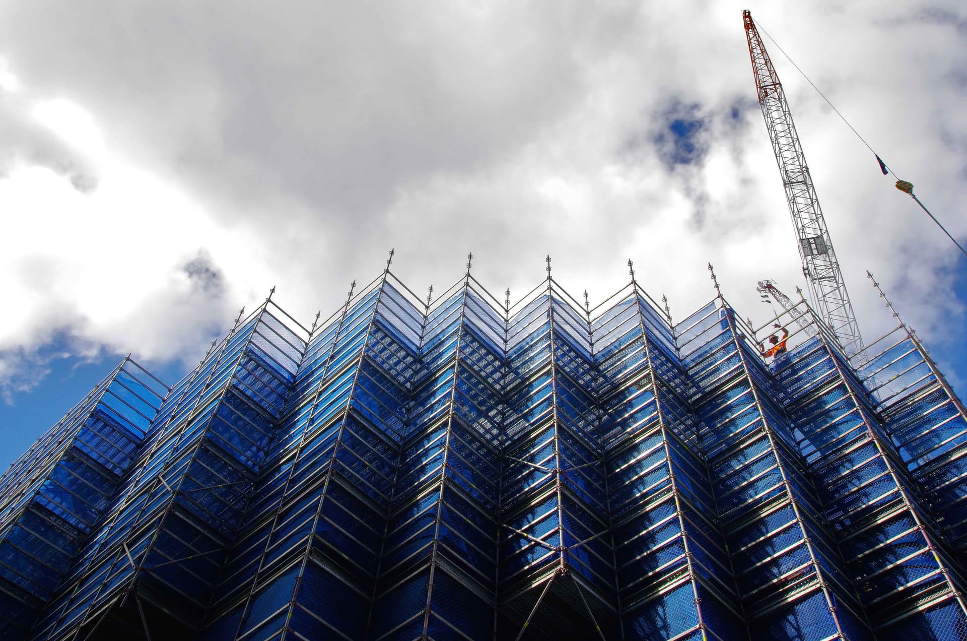 Professional Kwikstage scaffolding structure with blue safety mesh against dramatic sky